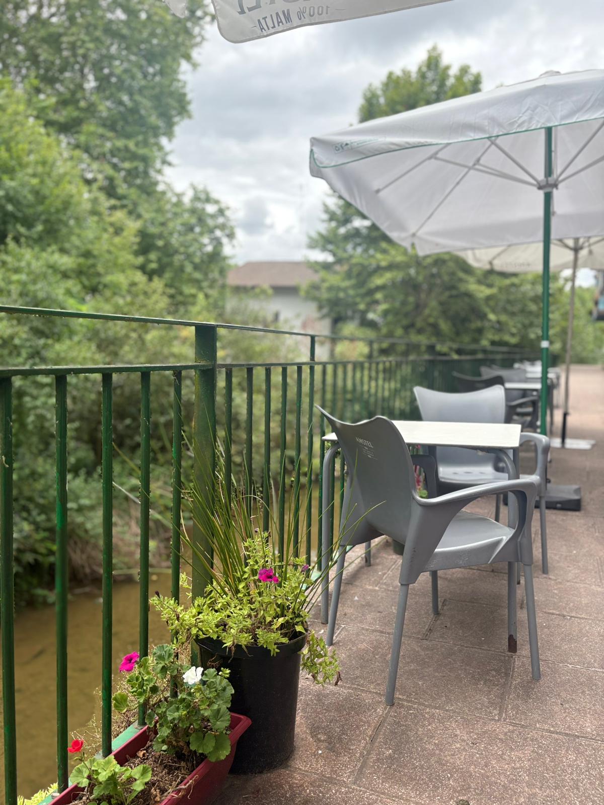 Rincón íntimo de la terraza de Sara Kafetegia con silla gris, maceta de flores y vistas al río Bidasoa